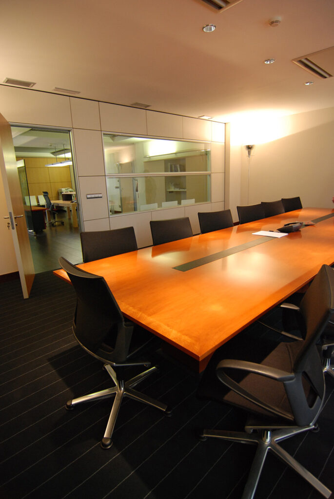 Sala de reuniones con mesa grande de madera y sillas negras de oficina