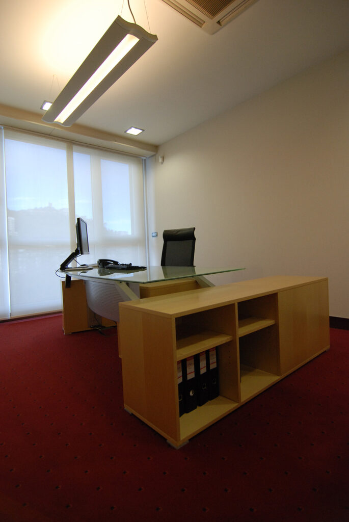 Despacho amplio con mesa de cristal y mueble de madera bajo