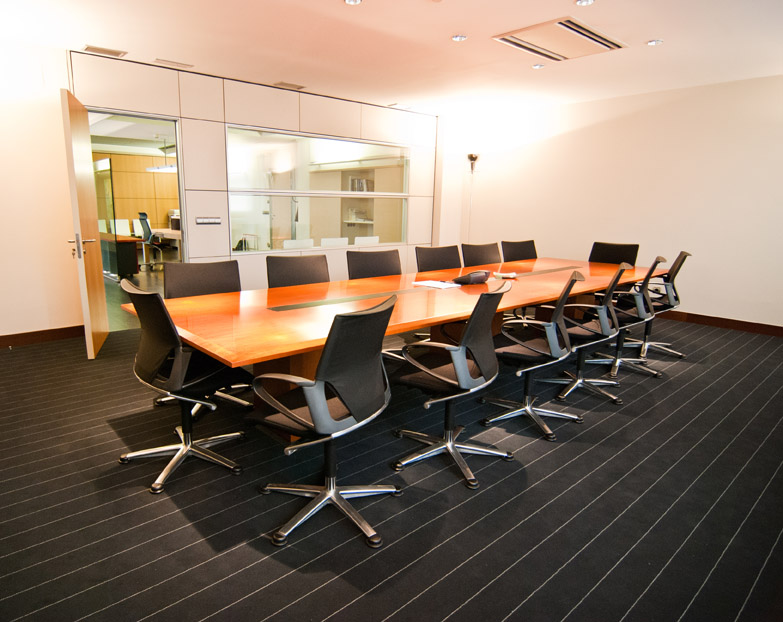 Sala de reuniones amplia con mesa muy larga y sillas de oficina